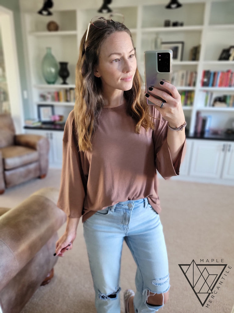 Jenise wears a light brown tunic with light blue jeans